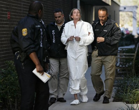 Tampa Police officers escort Julie Powers Schenecker to Orient Road Jail, in Tampa, Fla., on Friday. Police said Schenecker admitted to killing her teenage daughter and son after officers found her covered in blood on the back porch of her home Friday morning, police spokeswoman Laura McElroy said. 